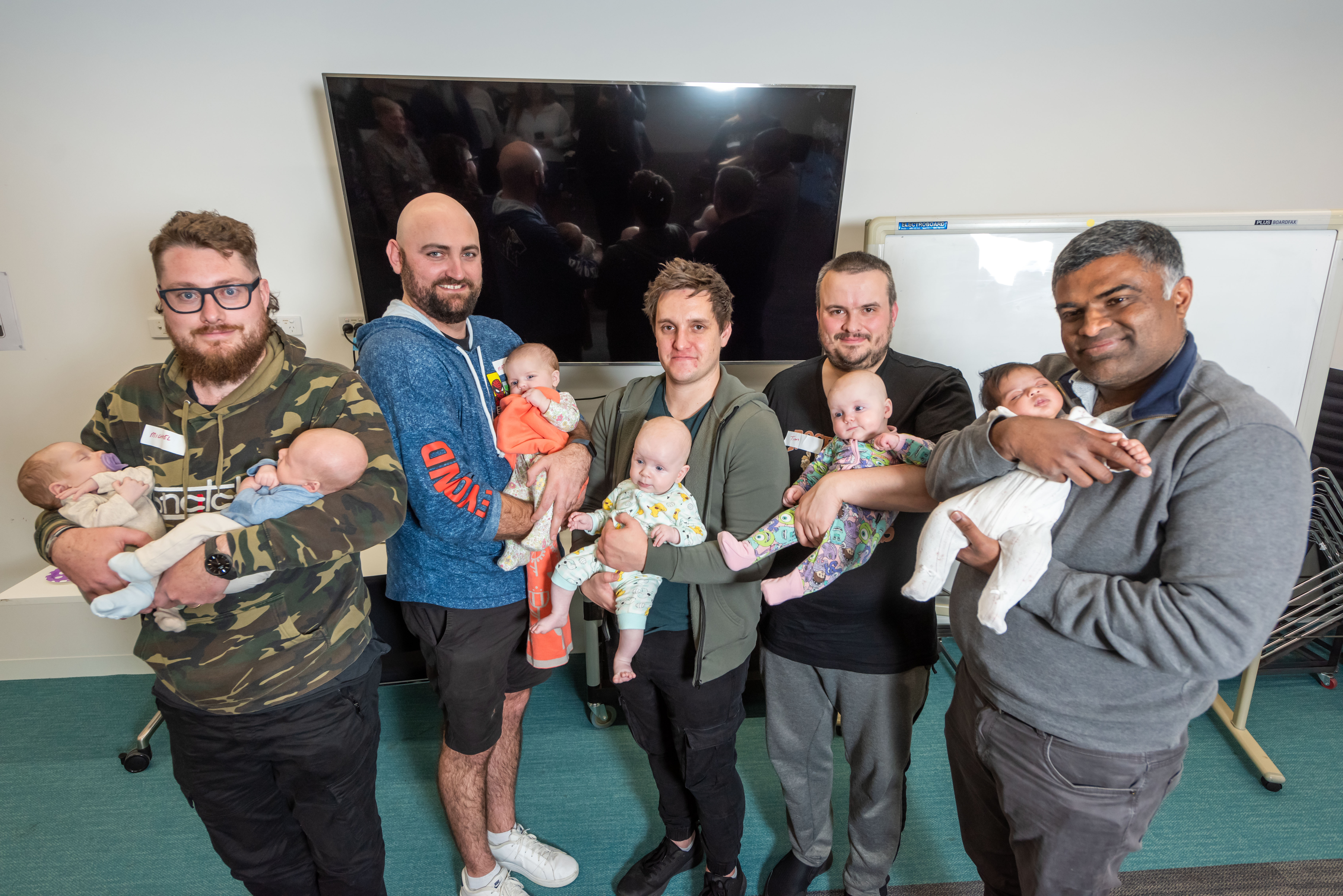 Five proud dads and their adorable babies celebrate completing the Cardinia Dads Program with big smiles all around