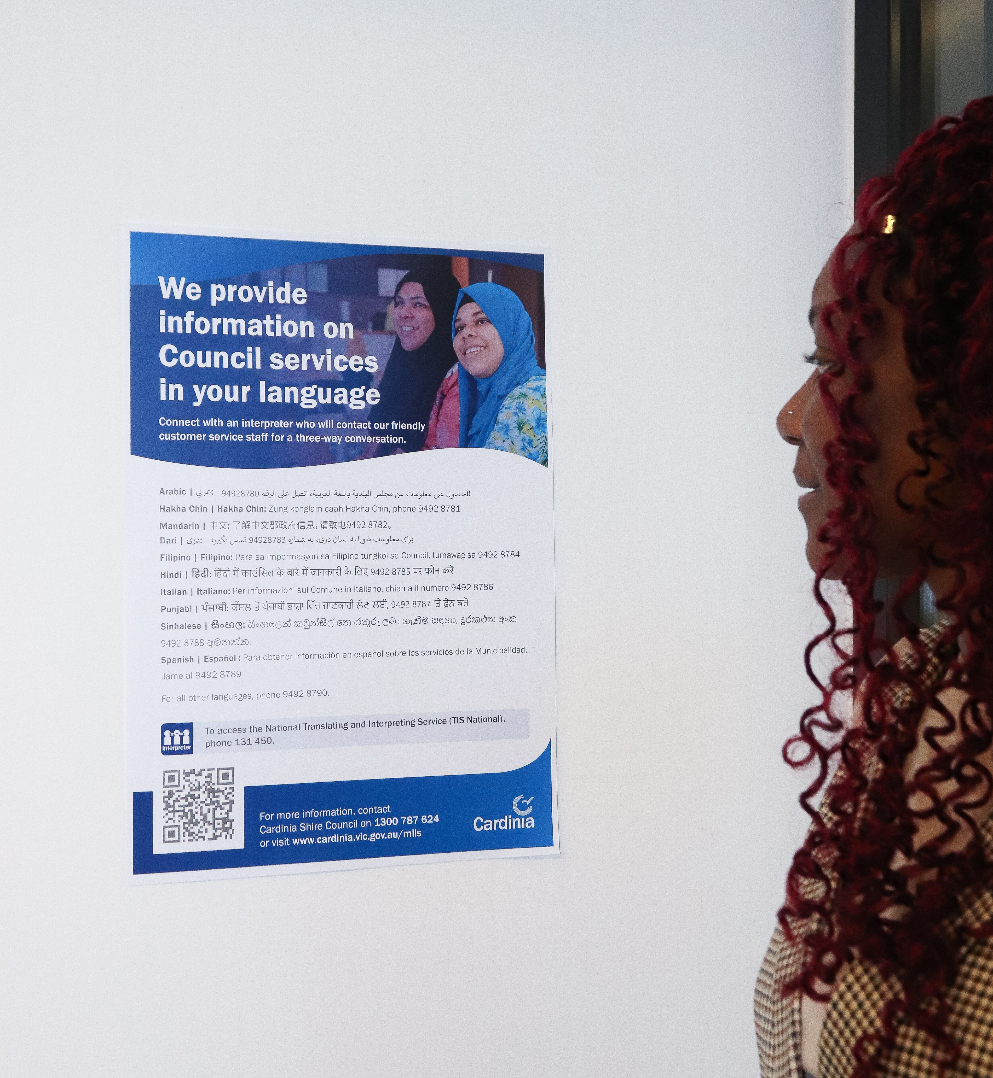 Woman reading a poster with information about the Multilingual Information Line Service.